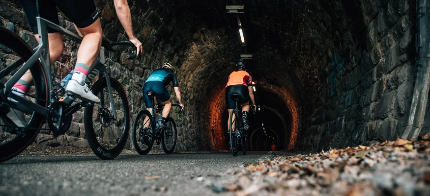 Radfahrer fahren durch einen beleuchteten Steintunnel auf der Straße