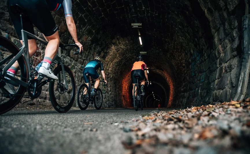 Radfahrer fahren durch einen beleuchteten Steintunnel auf der Straße