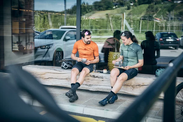 Slowenien © Tobias Köhler Zwei Radfahrer in Sportkleidung trinken Kaffee auf einer Holzbank draußen