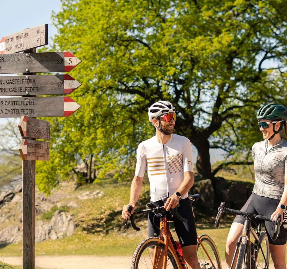 Auf Schotterkurs im Hotel Teutschhaus © Cinemepic / Teutschhaus Zwei Radfahrer sprechen an einem Wegweiser im Grünen bei Sonnenschein