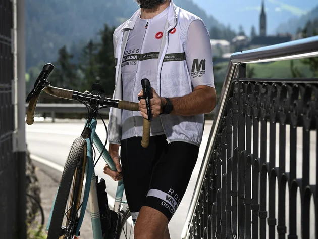 Gravel & Genuss am Kronplatz © Hotel Ostaria Posta Mann mit Fahrrad und Helm steht vor Berglandschaft