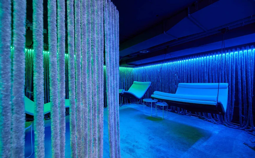 Moderne blaue Lounge mit schwebenden Sitzmöbeln und atmosphärischer Beleuchtung