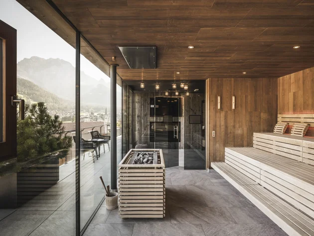 Herbst auf Schotter im Excelsior Dolomites Life Resort****s © Hannes Niederkofler Moderner Sauna-Innenraum mit Holzwänden und großem Fenster mit Bergblick