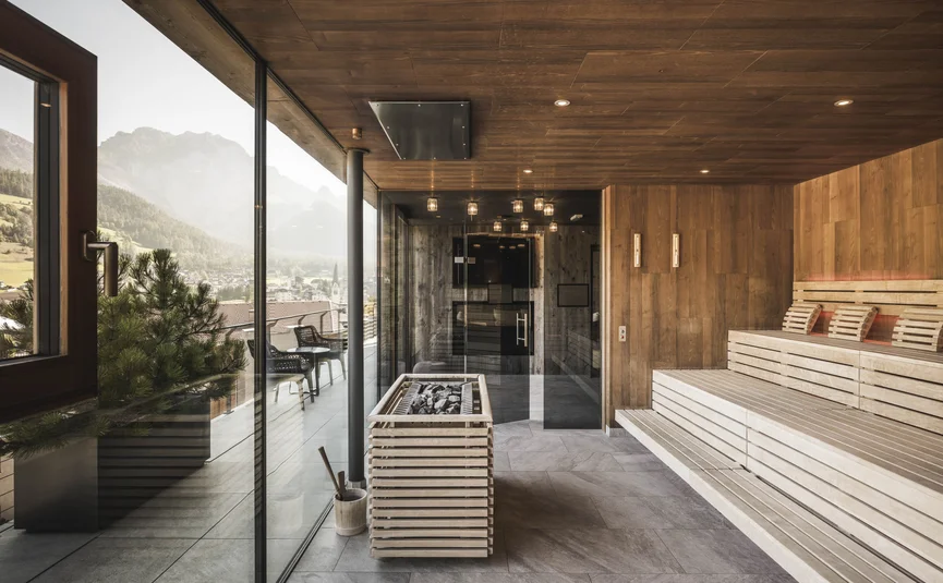Excelsior Dolomites Life Resort ****S © Hannes Niederkofler Moderner Sauna-Innenraum mit Holzwänden und großem Fenster mit Bergblick