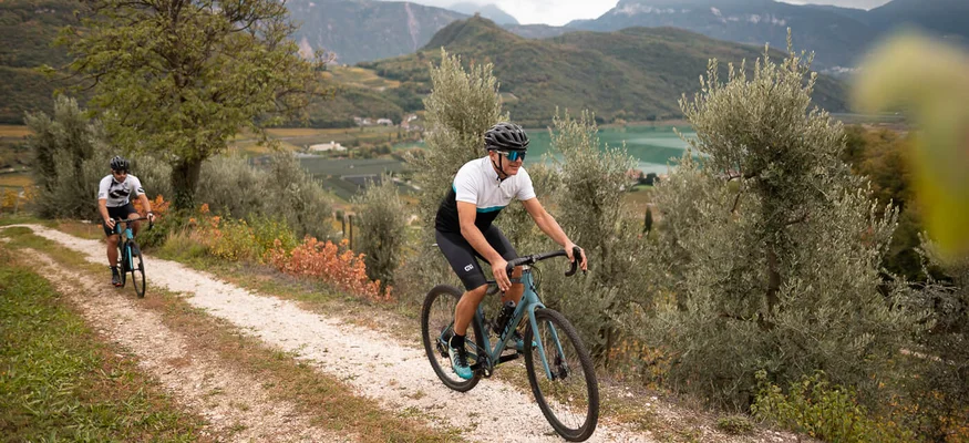 Two cyclists riding on a path in mountainous landscape with lake background
