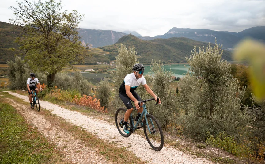 Two cyclists riding on a path in mountainous landscape with lake background