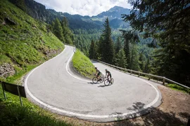 Gravel bike holiday at Lake Levico © Heiko Mandl Two cyclists on a hairpin road in a mountainous forest area