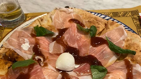 Bikepacking von Wien nach Athen © Jan Koller Pizza mit dünnen Schinkenstücken, Basilikum und Mozzarella auf einem Teller