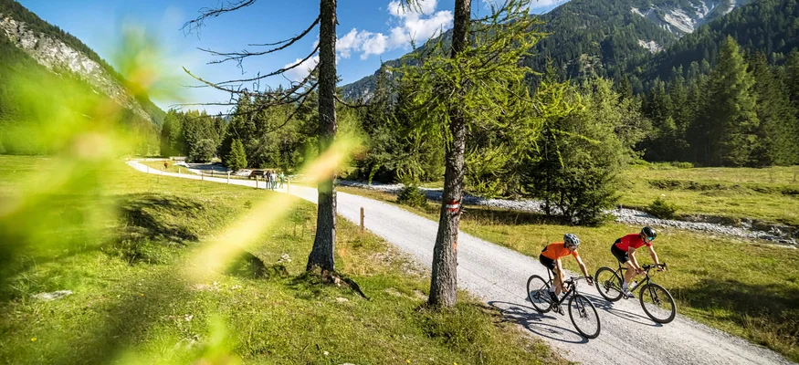 Aktivhotel Alpendorf **** © SalzburgerLand Tourismus Zwei Radfahrer fahren auf einem Waldweg in den Bergen bei klarem Himmel