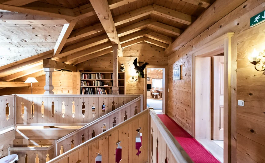 Hallway in a wooden house with bookshelf and red carpet