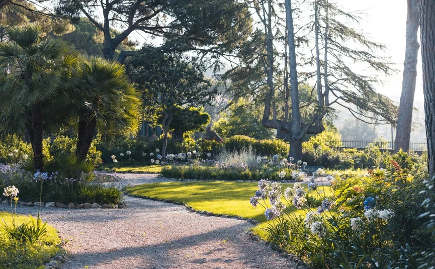 Tenuta Il Cicalino © Tenuta il Cicalino Weg durch blühenden Garten mit Bäumen und Sonnenlicht