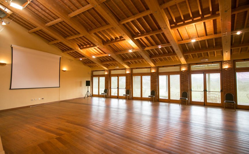 Leerer Raum mit Holzboden, Holzbalkendecke und Projektorleinwand