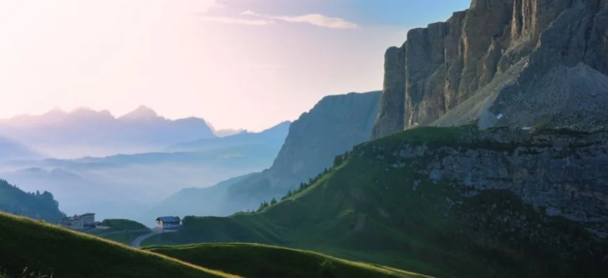 Blick auf grüne Hügel und steile Felsen in den Bergen bei Sonnenaufgang