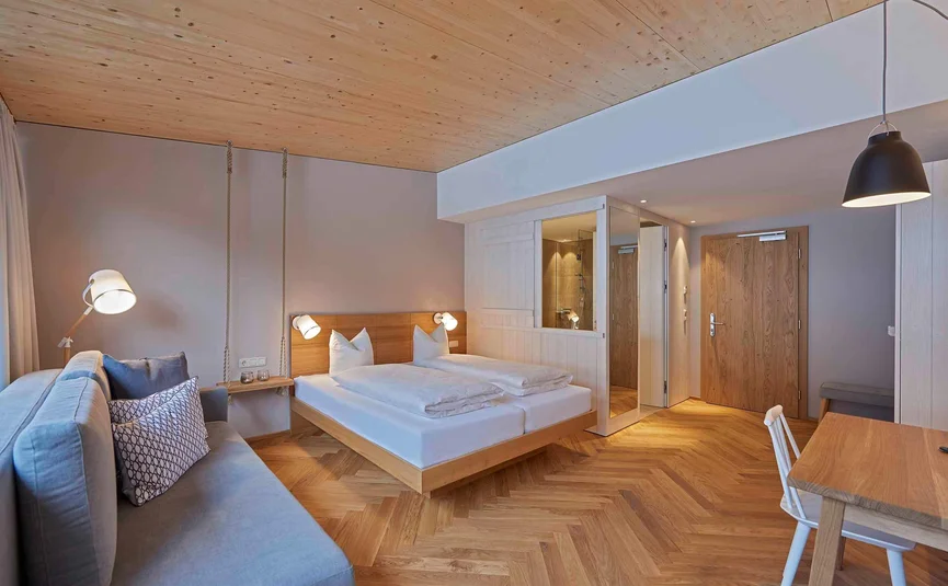 Modernes Hotelzimmer mit Doppelbett, Sofa und Holzboden