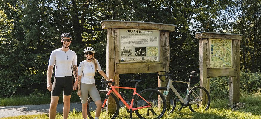 Landrefugium Obermüller ****S © Stefan J. Wolf Photography Zwei Radfahrer neben Infotafeln und ihren Fahrrädern im Grünen bei Sonnenschein