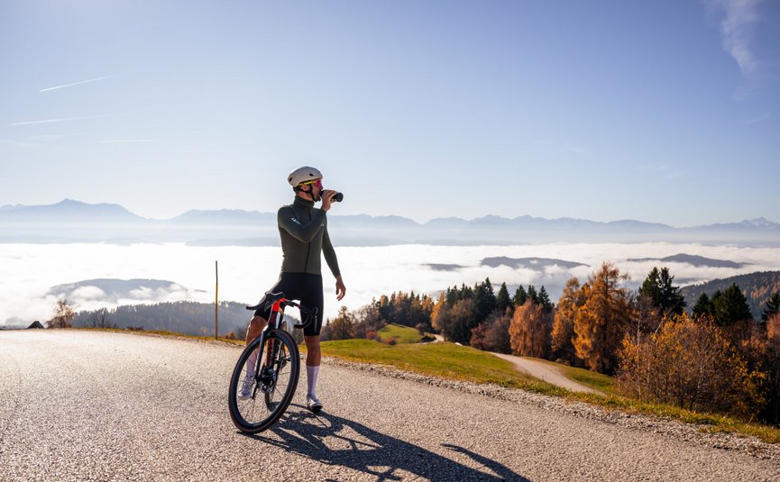 Cyclist pauses to drink water overlooking foggy mountains and autumn trees