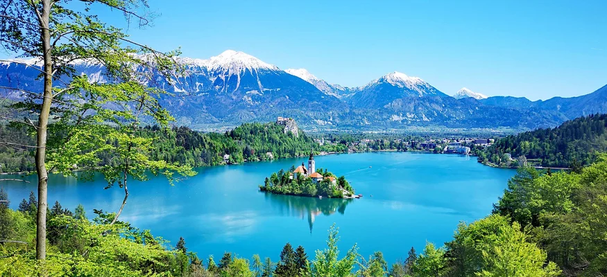 View of Lake Bled with island and church against snowy mountains