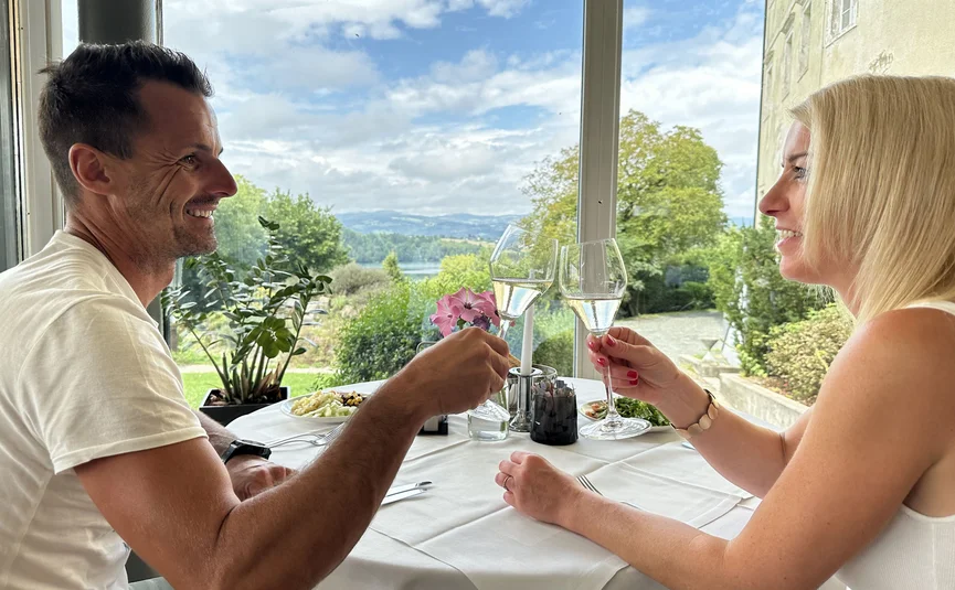 Paar stößt mit Sektgläsern in einem Restaurant mit Landschaftsblick an
