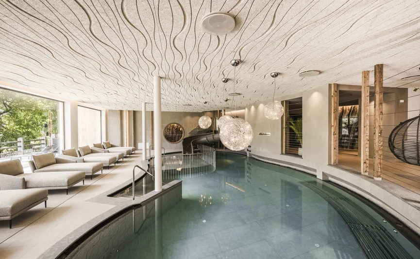 Modern spa area with pool, loungers, and wavy ceiling design