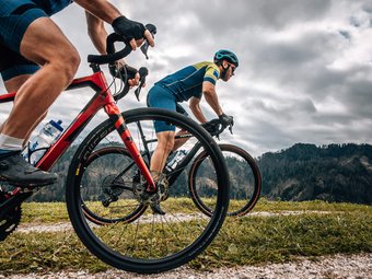 Zwei Radfahrer fahren auf einem Bergpfad bei bewölktem Himmel