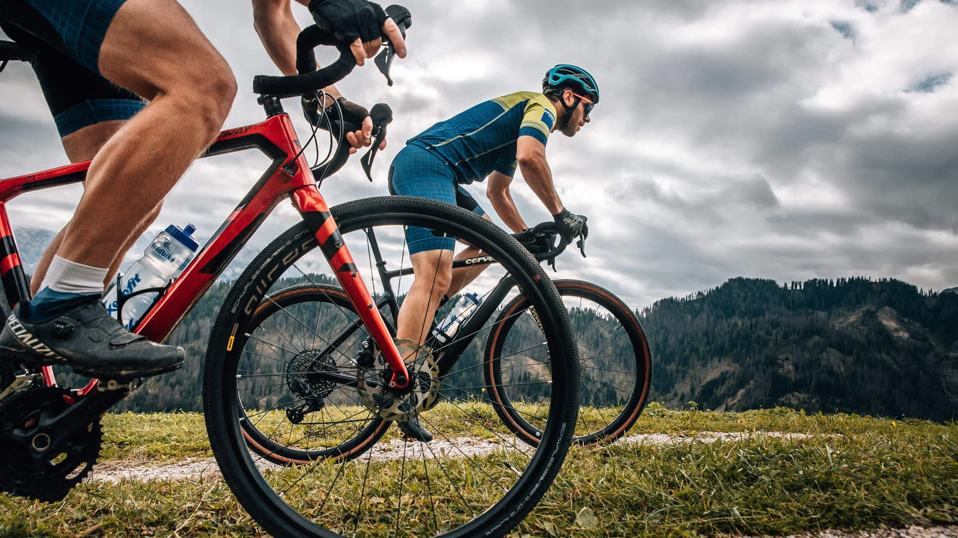 Zwei Radfahrer fahren auf einem Bergpfad bei bewölktem Himmel