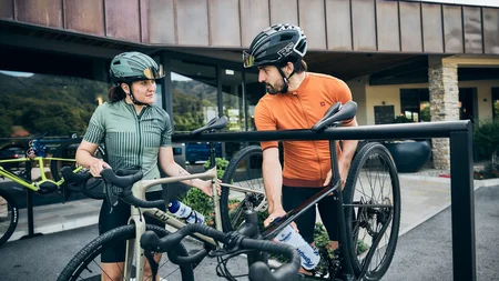Qualitätsversprechen © Tobias Köhler Fahrradfahrer mit Helm parken ihre Rennräder an einem Fahrradständer