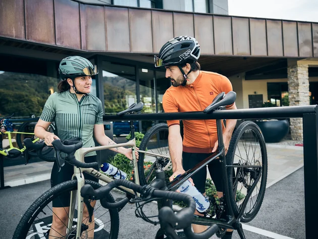 Qualitätsversprechen © Tobias Köhler Fahrradfahrer mit Helm parken ihre Rennräder an einem Fahrradständer