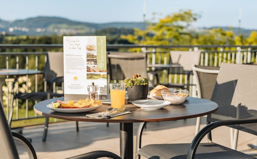 Frühstückstisch mit Speisen und Getränken auf Terrasse mit Bergblick