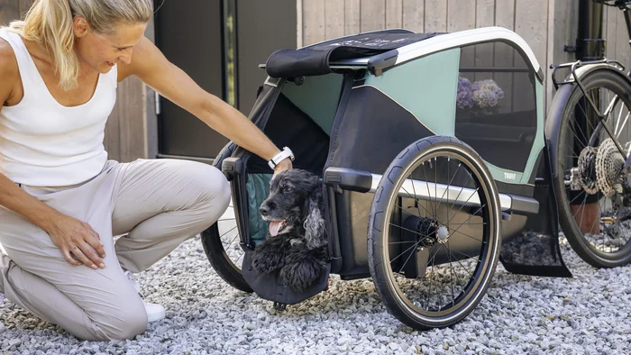 Mit dem Thule Bexey beginnt jedes Abenteuer zu zweit © Thule Frau streichelt einen Hund in einem Fahrradanhänger