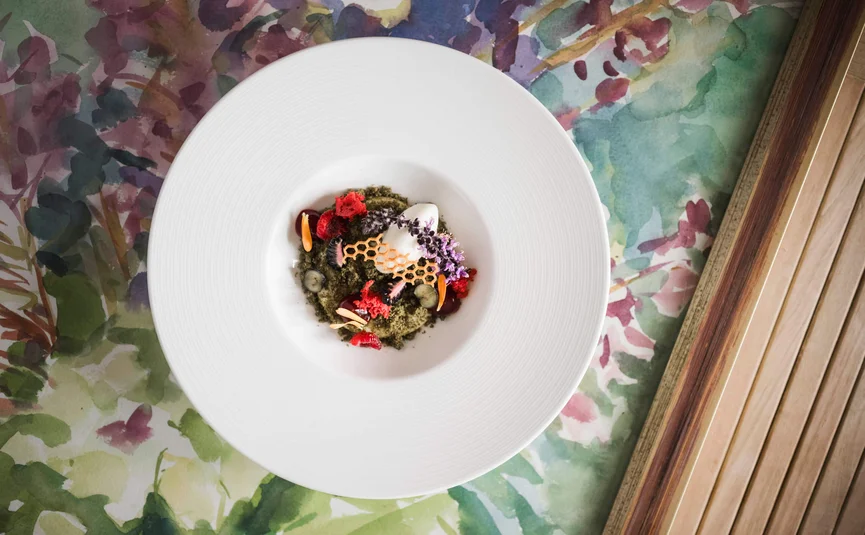 Artfully plated dessert with edible flowers on white plate