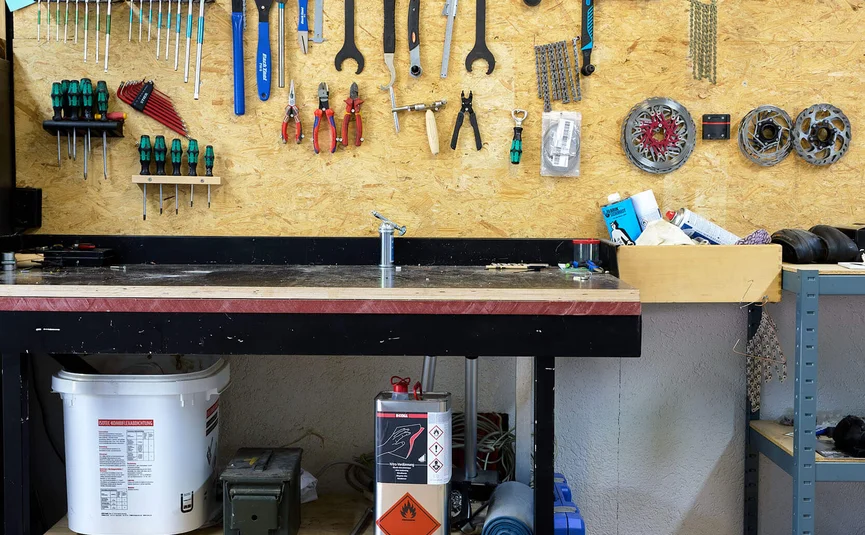 Worktable with neatly arranged bicycle tools and spare parts on the wall