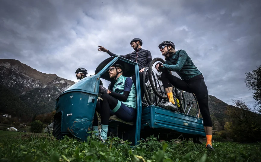 Gravel bike holiday on Northern Lake Garda © Gijs Ferkranus - Wielrenblad Magazine Four cyclists with helmets on a blue three-wheeled vehicle in the mountains
