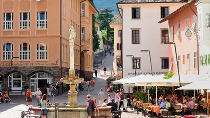 Touristen sitzen an einem Brunnen und in einem Straßencafé in einer europäischen Stadt