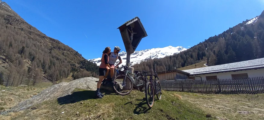 Central goes Gravel!
© Hartmann Ploner Radfahrer und Begleiter vor Bergkreuz mit schneebedeckten Alpen