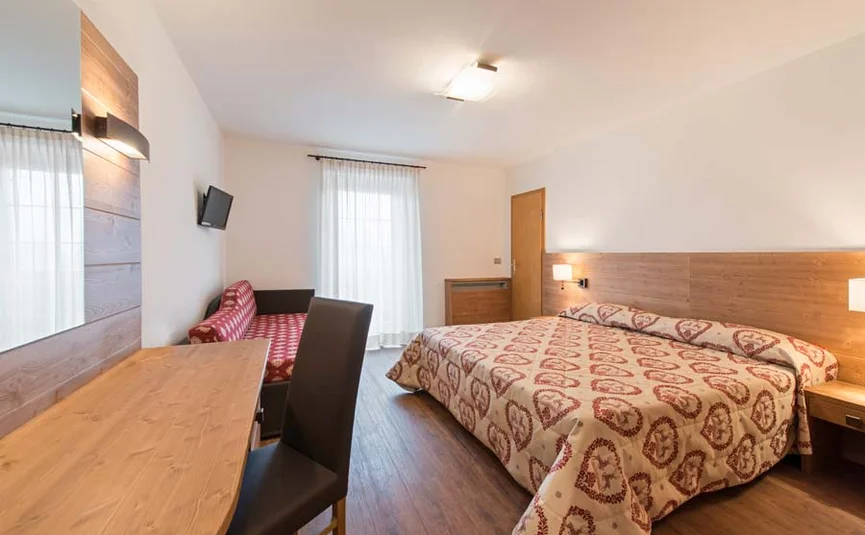 Hell eingerichtetes Hotelzimmer mit Doppelbett und Schreibtisch