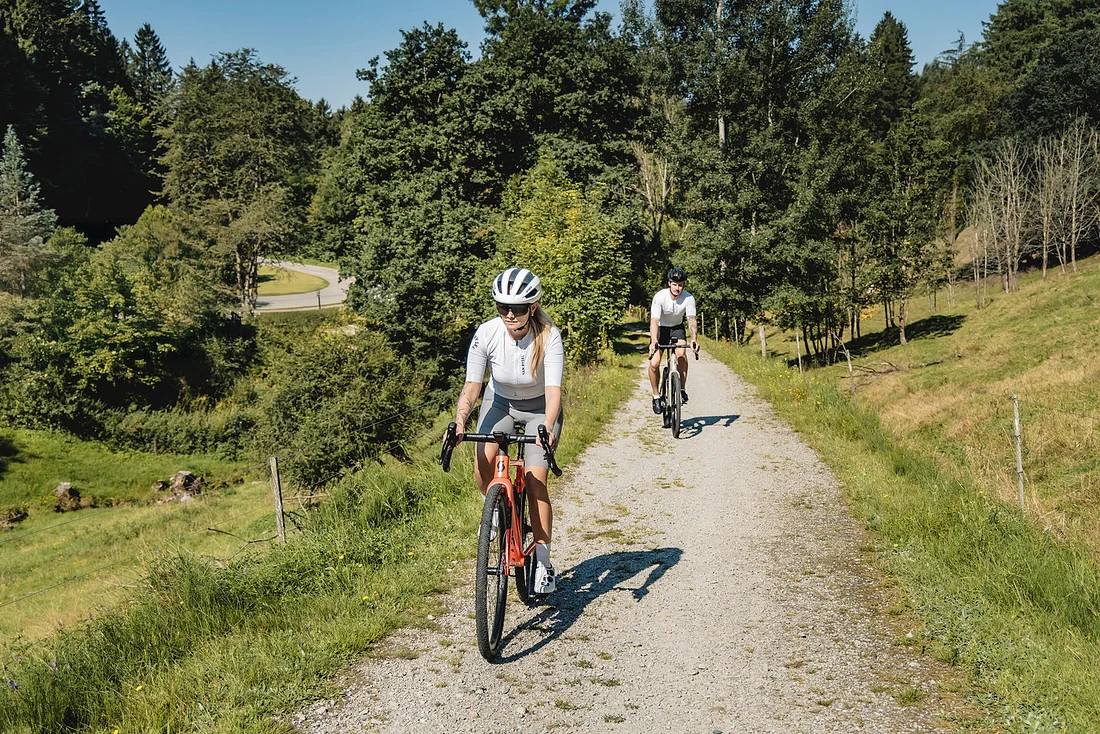 Gravelbiken im Bayerischen Wald © Stefan J. Wolf Photography Zwei Radfahrer auf einem Waldweg bei sonnigem Wetter