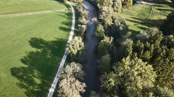 Deutschland © Oberbayern.de - Tobias Köhler Luftaufnahme eines Flusses mit Bäumen und einem Weg daneben in einer ländlichen Umgebung