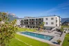 Modern apartment building with pool and mountain view under clear blue sky