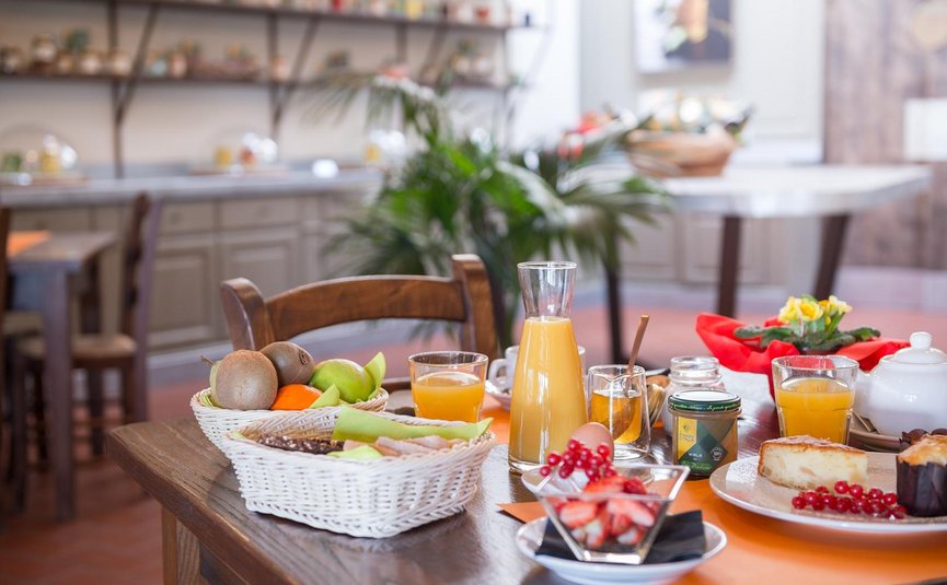 Frühstückstisch mit Obst, Saft, Kuchen und Getränken in einem gemütlichen Raum