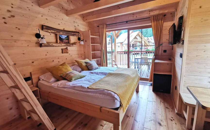 Modern wooden bedroom with double bed and balcony with outdoor seating