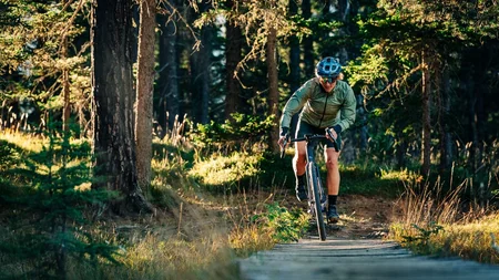 Das waren die Golden Days in Nauders © TVB-Tiroler-Oberland-Nauders-Christian-Penning - Gravelbiken in Nauders Radfahrer fährt auf einem Holzsteg durch einen sonnigen Wald