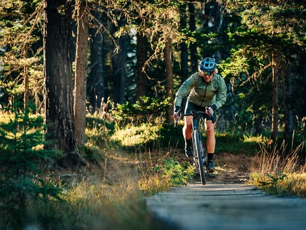Das waren die Golden Days in Nauders © TVB-Tiroler-Oberland-Nauders-Christian-Penning - Gravelbiken in Nauders Radfahrer fährt auf einem Holzsteg durch einen sonnigen Wald