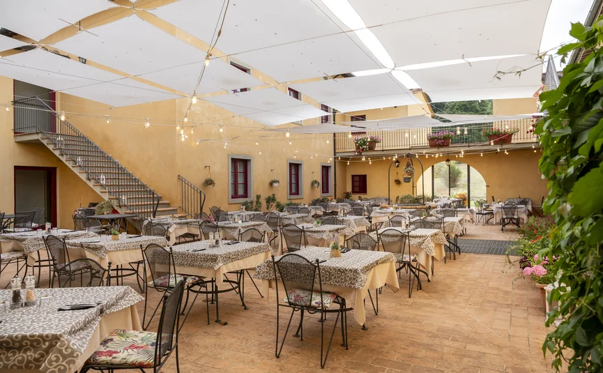 Outdoor restaurant with tables, chairs, sun sails, and hanging string lights