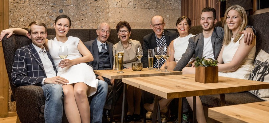 Familie sitzt zusammen in gemütlichem Raum mit Getränken auf dem Tisch