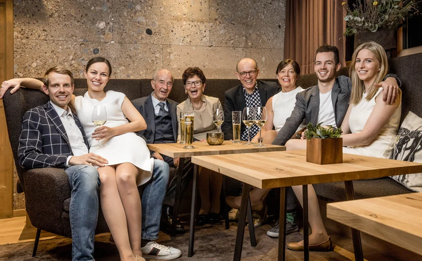Familie sitzt zusammen in gemütlichem Raum mit Getränken auf dem Tisch