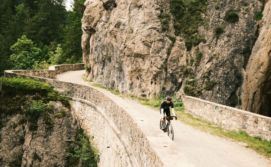 Radfahrer auf einem kurvigen Bergpfad neben einer Felswand