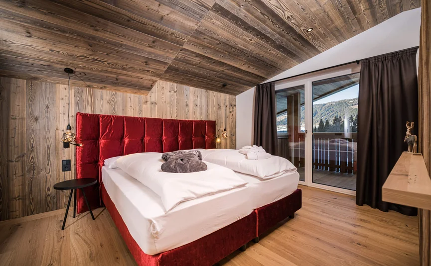 Cozy bedroom with red bed and wooden wall
