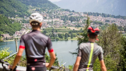 Two cyclists overlooking a lake and a town in the mountains