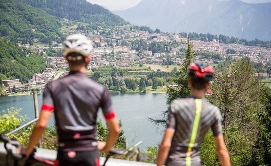 Gravel bike holiday at Lake Levico © Heiko Mandl Two cyclists overlooking a lake and a town in the mountains