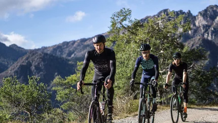 Three cyclists riding on a mountain trail in sunny weather